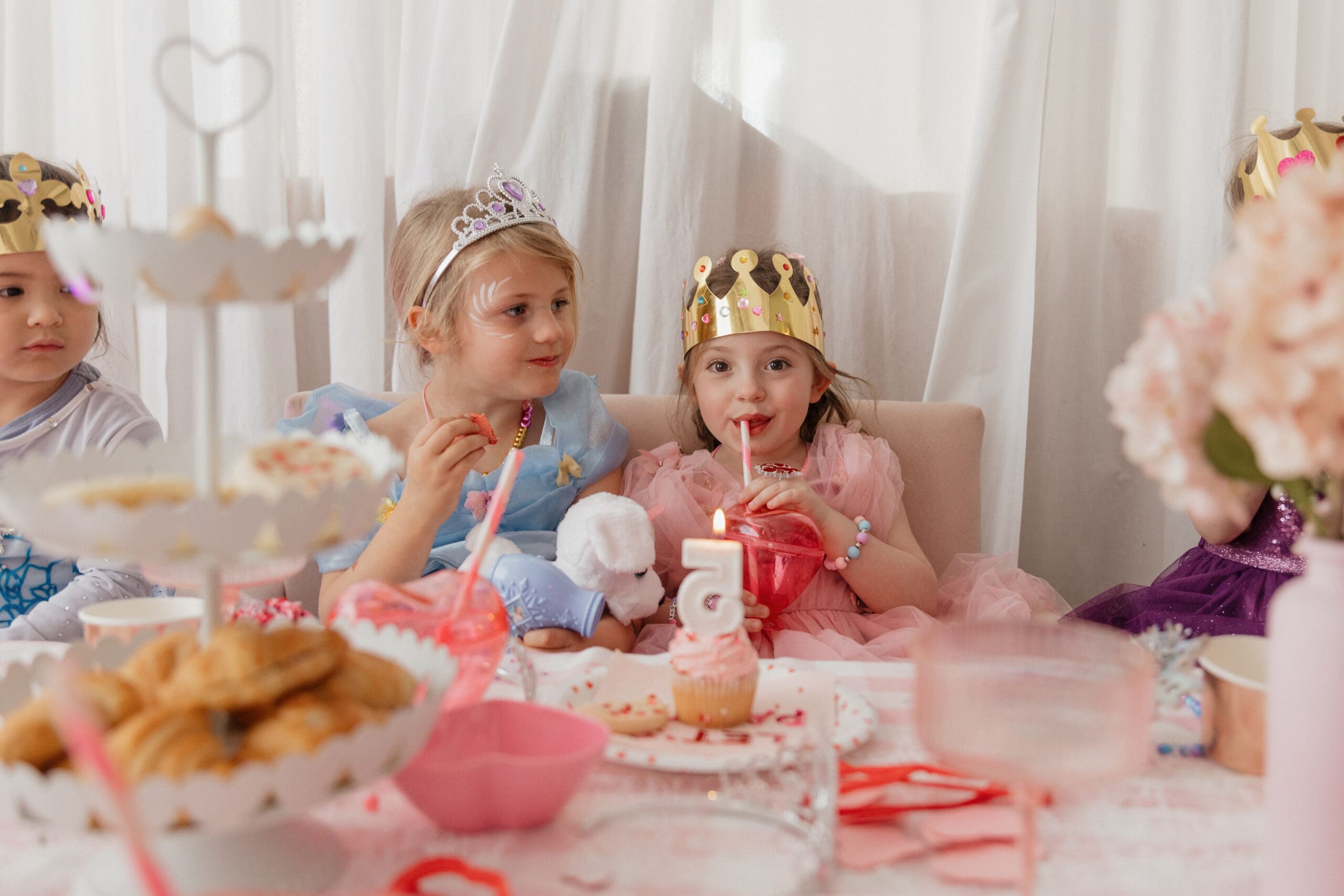 Child enjoying a princess tea party birthday with pink décor, themed crafts, and Valentine details at a Denver photo studio.